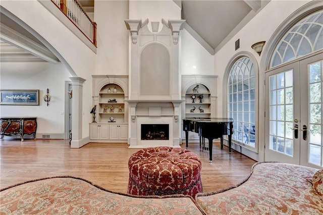 8455 Abingdon Ln, Duluth, GA 30097 - living area with high vaulted ceiling, french doors, built in features, light wood-style floors, and a fireplace with flush hearth