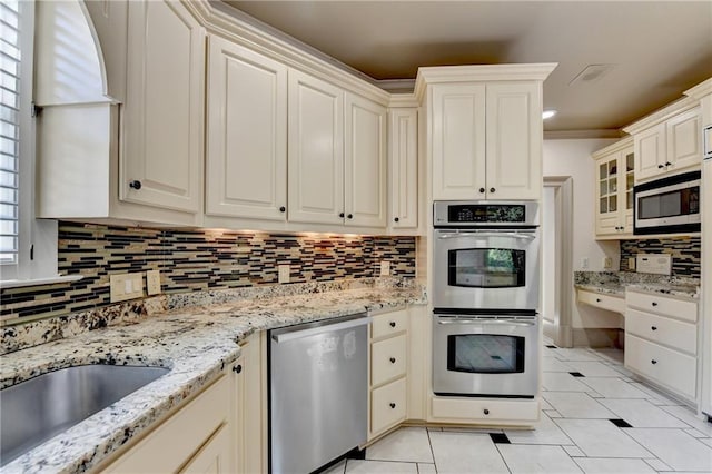 8455 Abingdon Ln, Duluth, GA 30097 - kitchen featuring appliances with stainless steel finishes, decorative backsplash, light tile patterned flooring, light stone counters, and ornamental molding