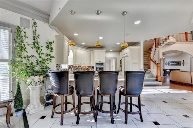 8455 Abingdon Ln, Duluth, GA 30097 - kitchen with oven, a peninsula, a breakfast bar area, decorative light fixtures, and arched walkways