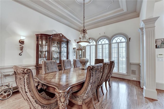 8455 Abingdon Ln, Duluth, GA 30097 - dining area featuring ornate columns, a tray ceiling, light wood-style flooring, crown molding, and a wainscoted wall