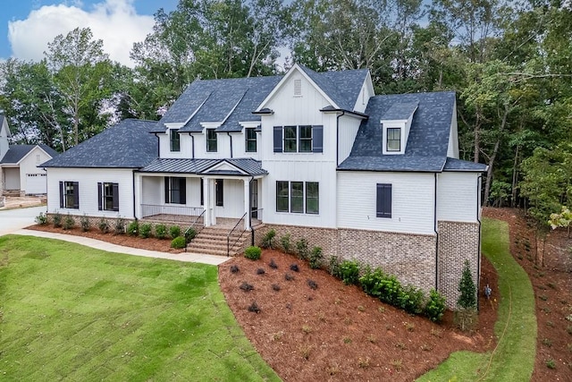 modern farmhouse style home with covered porch and a front yard