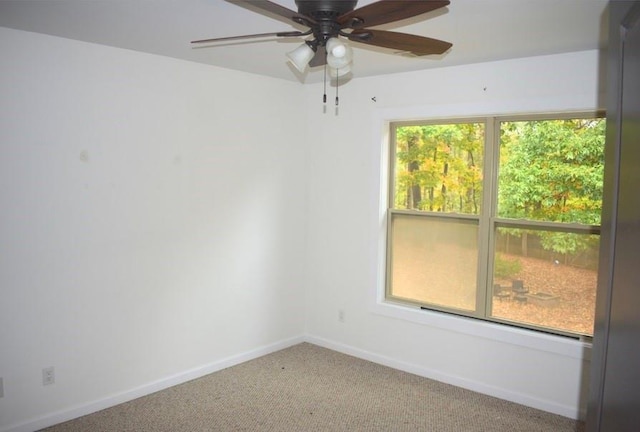 carpeted spare room with ceiling fan and plenty of natural light