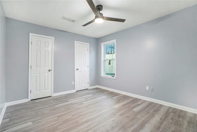 unfurnished bedroom with light wood-type flooring, two closets, and ceiling fan