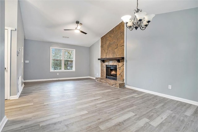 unfurnished living room with a fireplace, light wood-type flooring, vaulted ceiling, and ceiling fan with notable chandelier