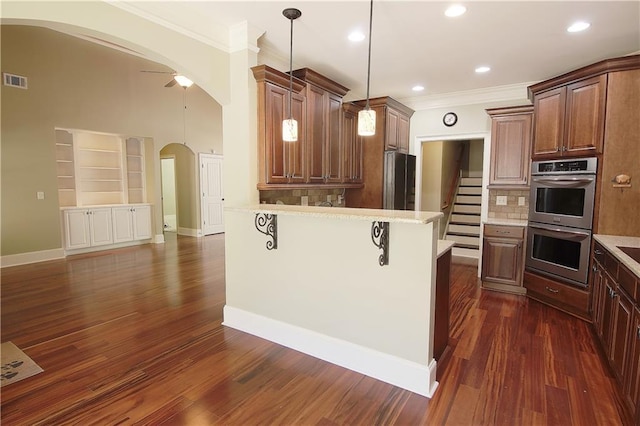 1520 Camden Cove Dr, Cumming, GA 30040 - kitchen featuring stainless steel double oven, ornamental molding, arched walkways, a kitchen bar, and light countertops