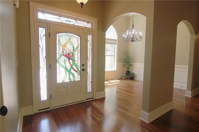 1520 Camden Cove Dr, Cumming, GA 30040 - foyer featuring arched walkways, wood finished floors, wainscoting, and a chandelier
