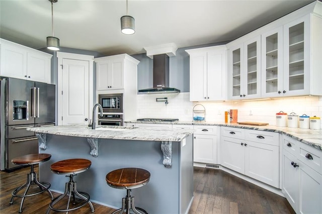 kitchen with a sink, appliances with stainless steel finishes, white cabinets, wall chimney range hood, and glass insert cabinets