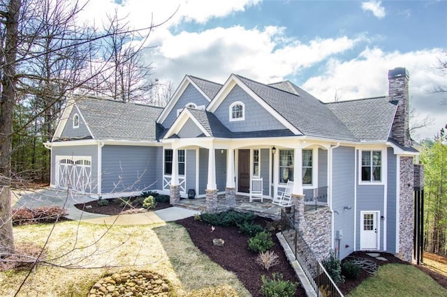 view of front of home with covered porch, concrete driveway, a shingled roof, a garage, and a chimney