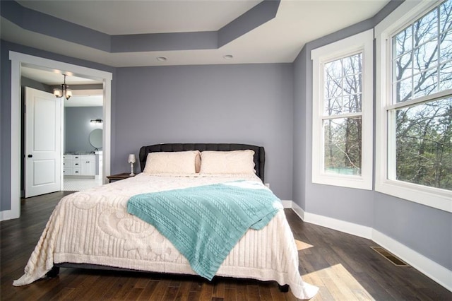 bedroom with visible vents, baseboards, multiple windows, and wood finished floors