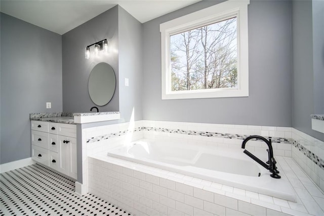 bathroom featuring baseboards, vanity, and a garden tub