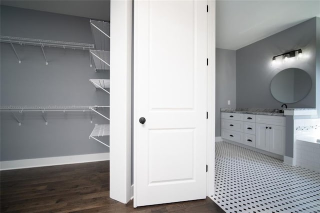 full bathroom with vanity, a spacious closet, wood finished floors, and baseboards