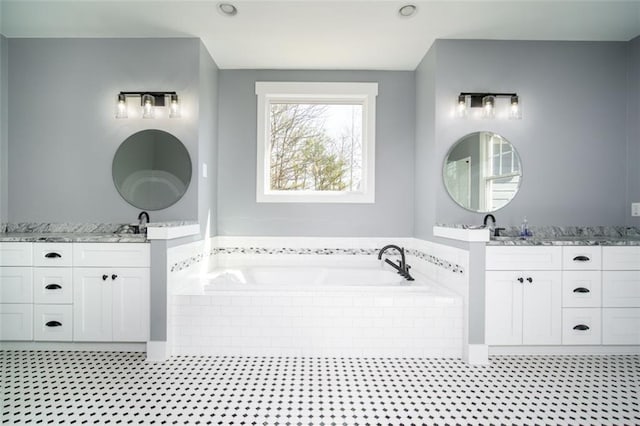 bathroom featuring a garden tub, two vanities, tile patterned floors, and a sink