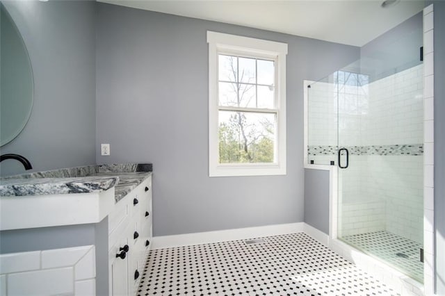 full bath with baseboards, vanity, and a shower stall