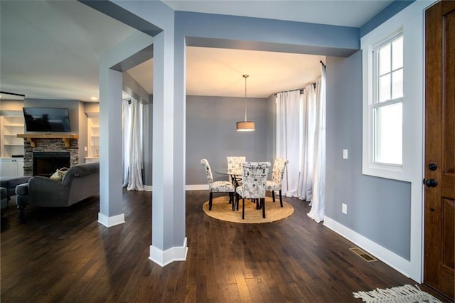 foyer entrance featuring dark wood finished floors, visible vents, a fireplace, and baseboards