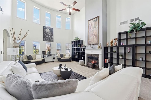 carpeted living room with a fireplace and ceiling fan