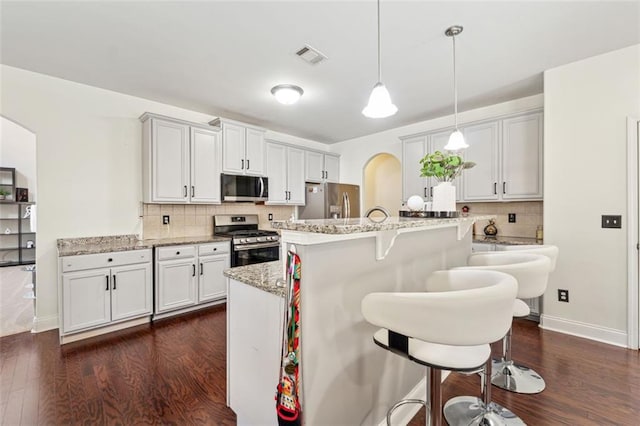 kitchen featuring pendant lighting, white cabinetry, stainless steel appliances, and a breakfast bar