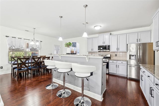 kitchen with white cabinetry, appliances with stainless steel finishes, decorative light fixtures, and a kitchen island