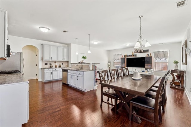 dining space with sink, a notable chandelier, and dark hardwood / wood-style flooring