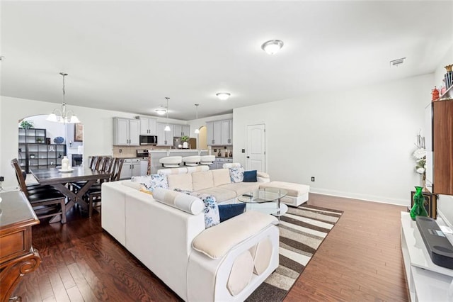 living room with dark wood-type flooring and a notable chandelier