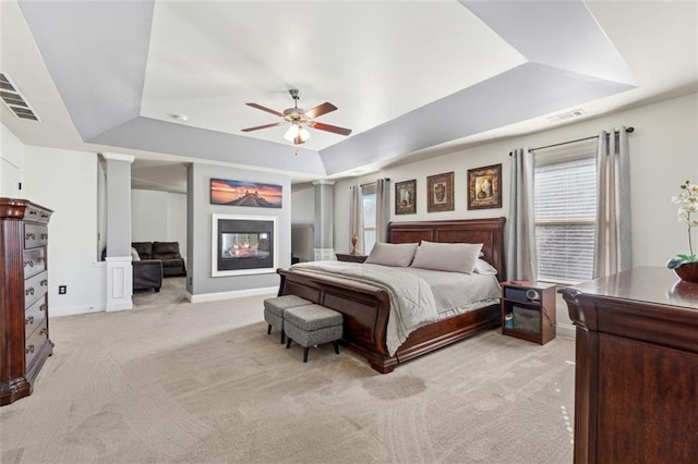 carpeted bedroom featuring multiple windows, a raised ceiling, and ceiling fan