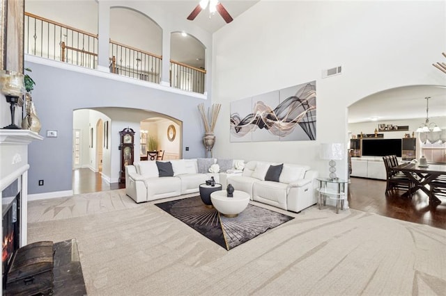 living room featuring ceiling fan with notable chandelier, a towering ceiling, and hardwood / wood-style floors