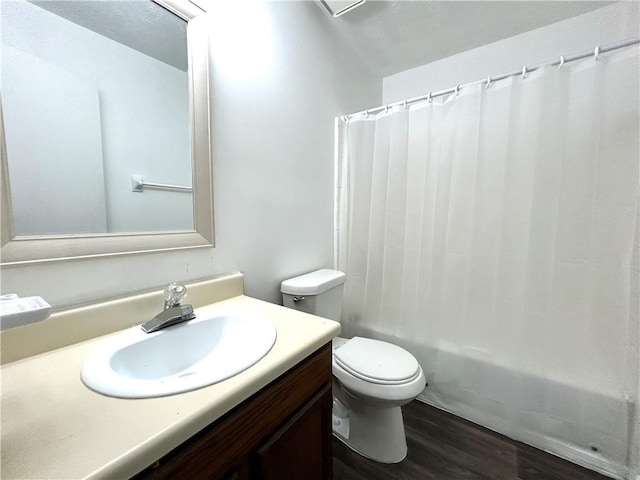 full bathroom featuring hardwood / wood-style flooring, vanity, shower / bath combination with curtain, and toilet