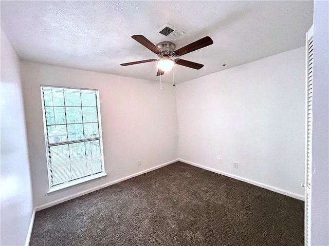 spare room with ceiling fan, dark carpet, and a textured ceiling