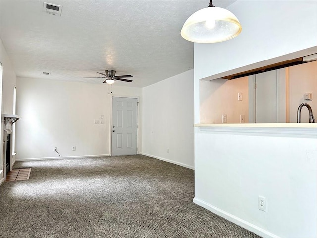 unfurnished living room with ceiling fan, sink, a textured ceiling, and dark colored carpet