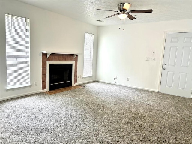 unfurnished living room with ceiling fan, a fireplace, a textured ceiling, and carpet