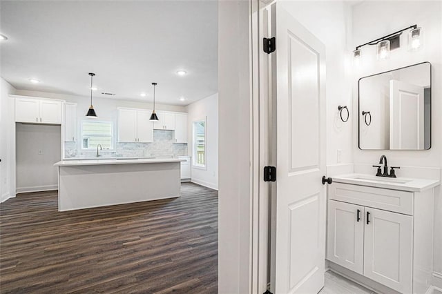 bathroom featuring two vanities, baseboards, wood finished floors, and a sink