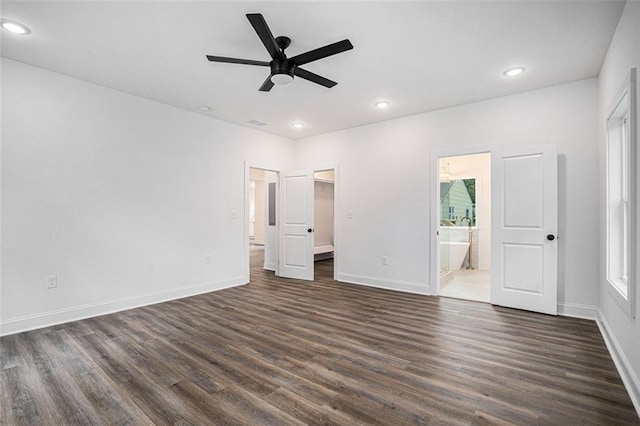 unfurnished bedroom featuring recessed lighting, dark wood finished floors, a spacious closet, connected bathroom, and baseboards