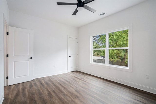 spare room featuring baseboards, wood finished floors, visible vents, and a ceiling fan