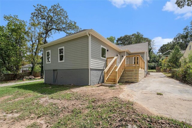 exterior space featuring fence, a lawn, a wooden deck, and stairs