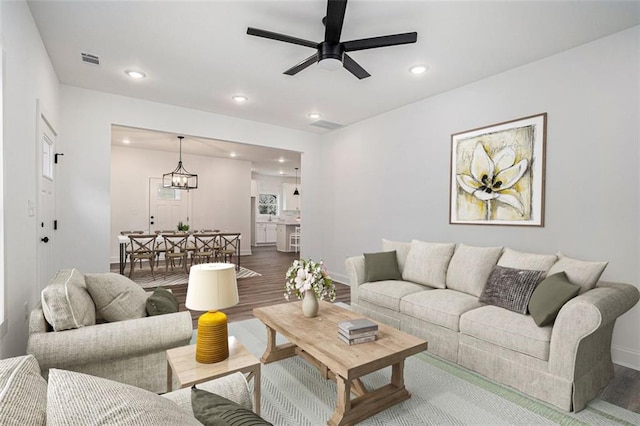 living room with recessed lighting, wood finished floors, visible vents, baseboards, and ceiling fan with notable chandelier