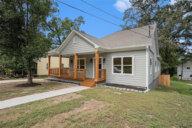 bungalow with covered porch, a front yard, and roof with shingles