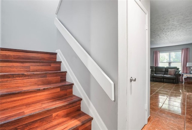 staircase featuring a textured ceiling and tile patterned floors