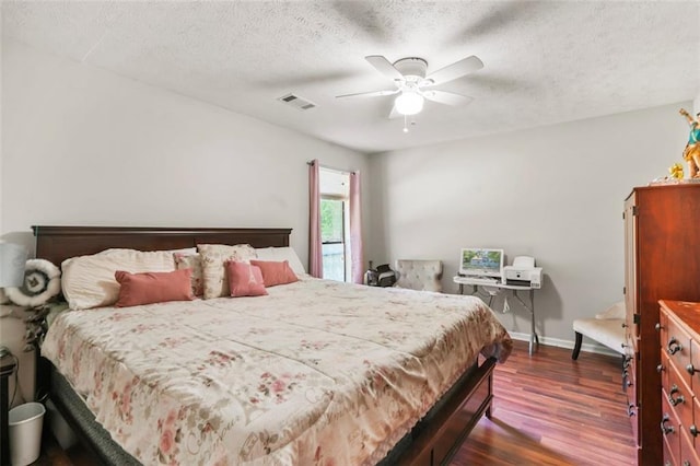 bedroom with ceiling fan, dark hardwood / wood-style floors, and a textured ceiling