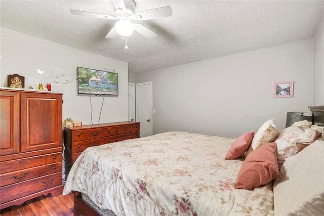 bedroom with hardwood / wood-style floors, ceiling fan, and a textured ceiling