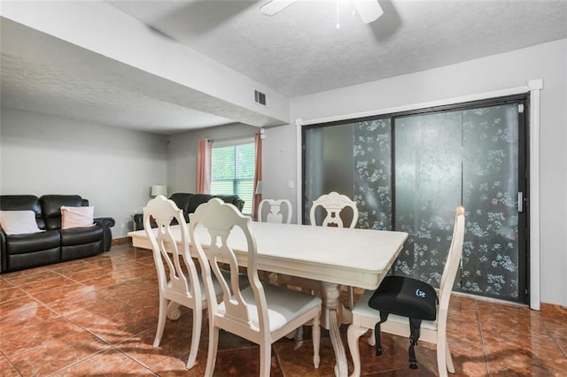 dining area with dark tile patterned flooring, ceiling fan, and a textured ceiling