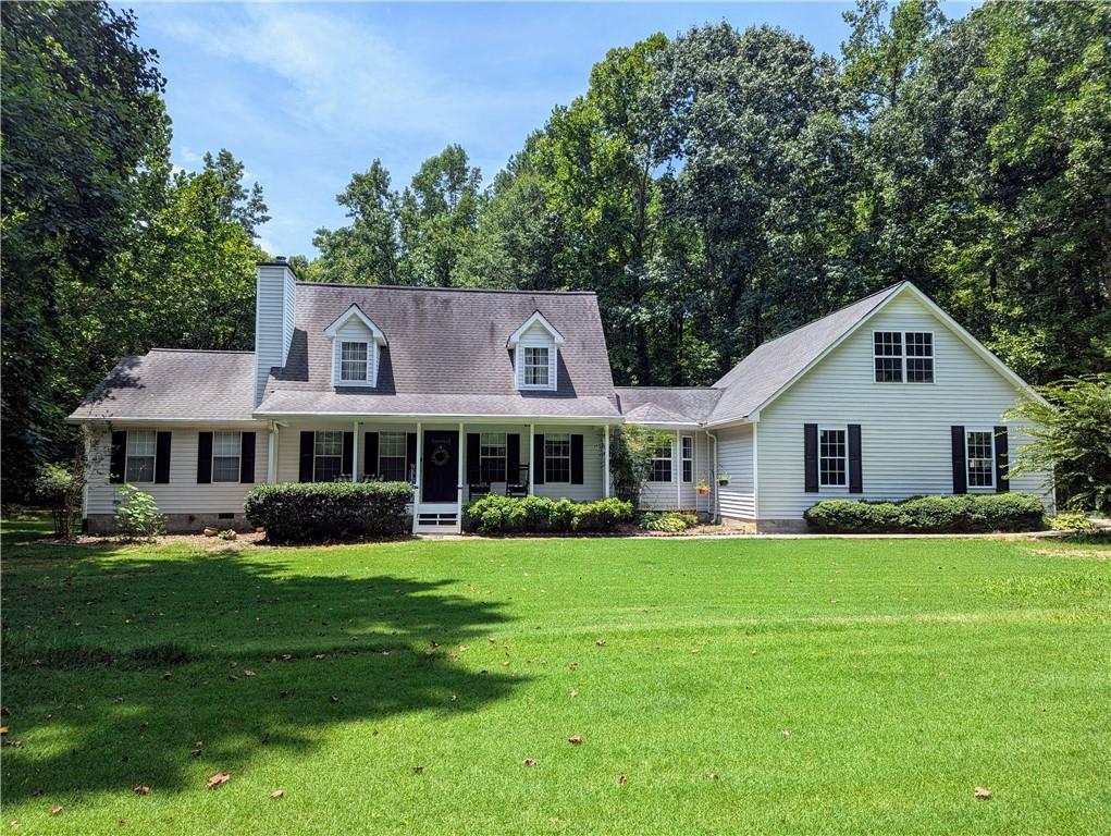 cape cod house with crawl space, a chimney, a porch, and a front yard