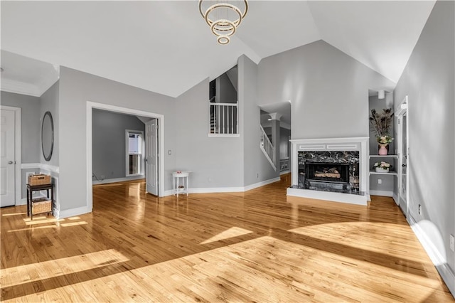 unfurnished living room featuring hardwood / wood-style floors, a chandelier, lofted ceiling, and a premium fireplace