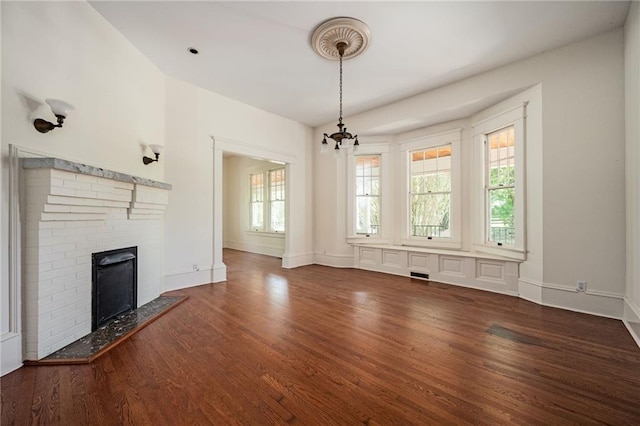 unfurnished living room featuring a brick fireplace and dark wood-type flooring