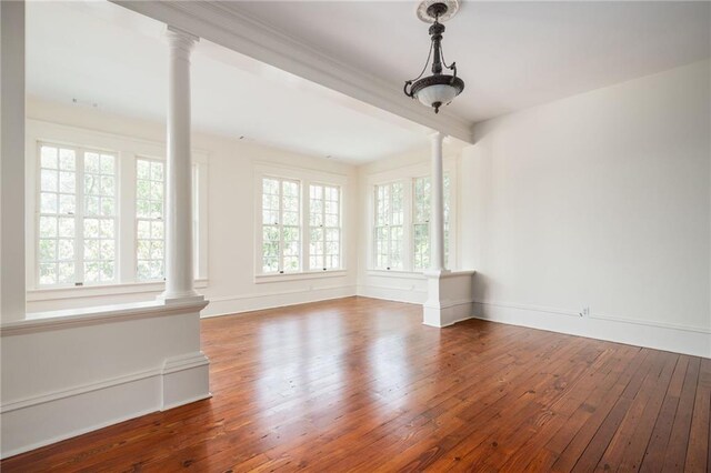 unfurnished room with decorative columns and hardwood / wood-style flooring