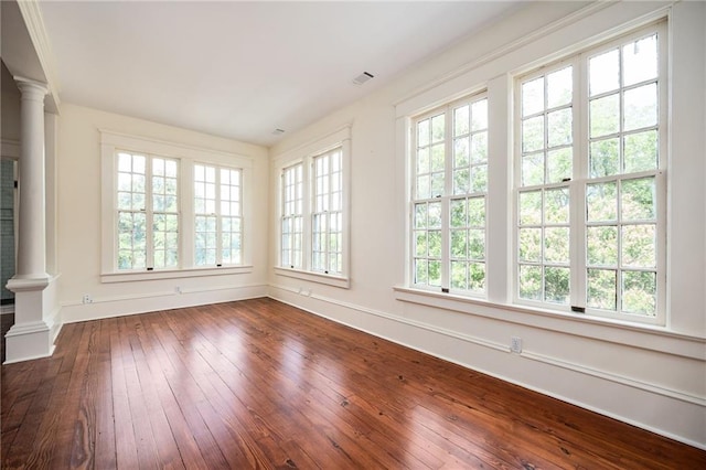 unfurnished sunroom with decorative columns