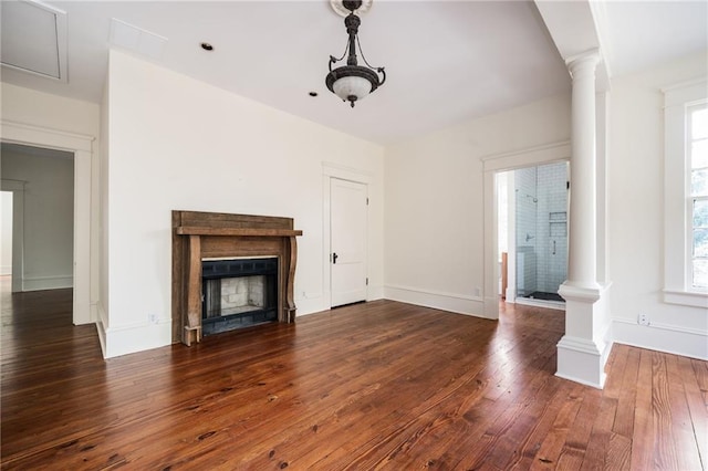 unfurnished living room with decorative columns, a healthy amount of sunlight, and dark hardwood / wood-style flooring