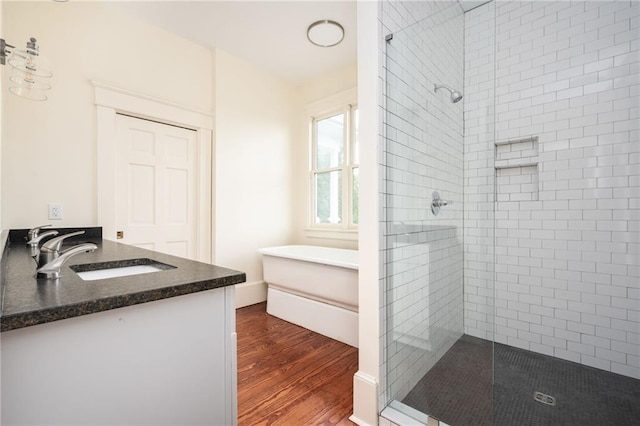 bathroom featuring vanity, wood-type flooring, and plus walk in shower