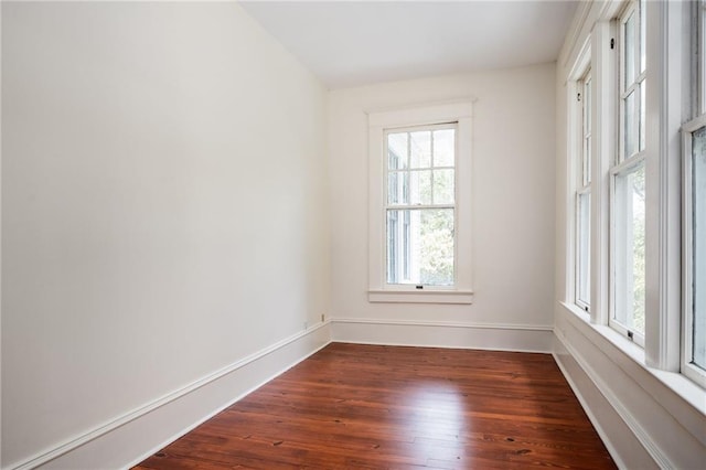 spare room featuring plenty of natural light and dark hardwood / wood-style flooring