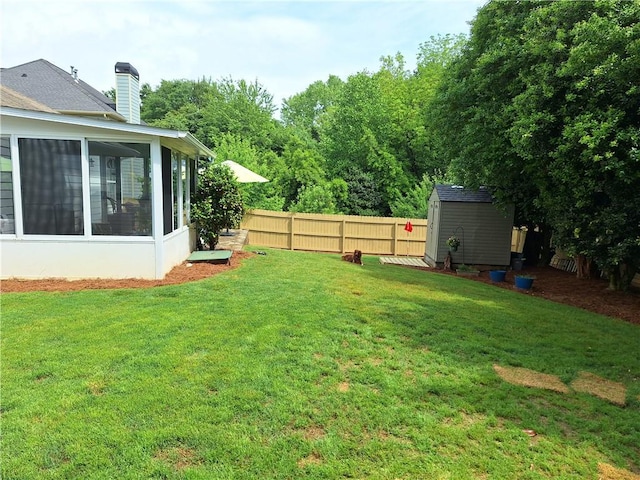 view of yard with a sunroom, a shed, an outbuilding, and fence
