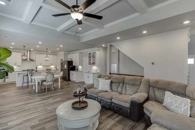 living room with wood-type flooring, coffered ceiling, crown molding, and beam ceiling