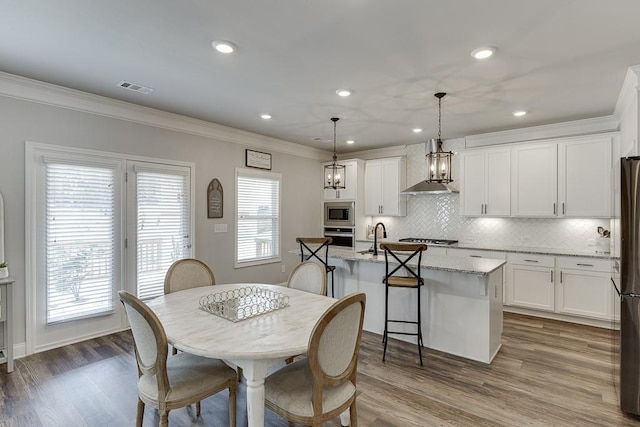 dining room featuring crown molding, sink, and hardwood / wood-style floors